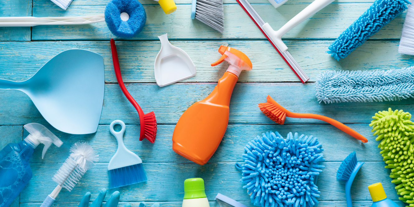 Aerial image, light blue background, a variety of cleaning supplies displayed